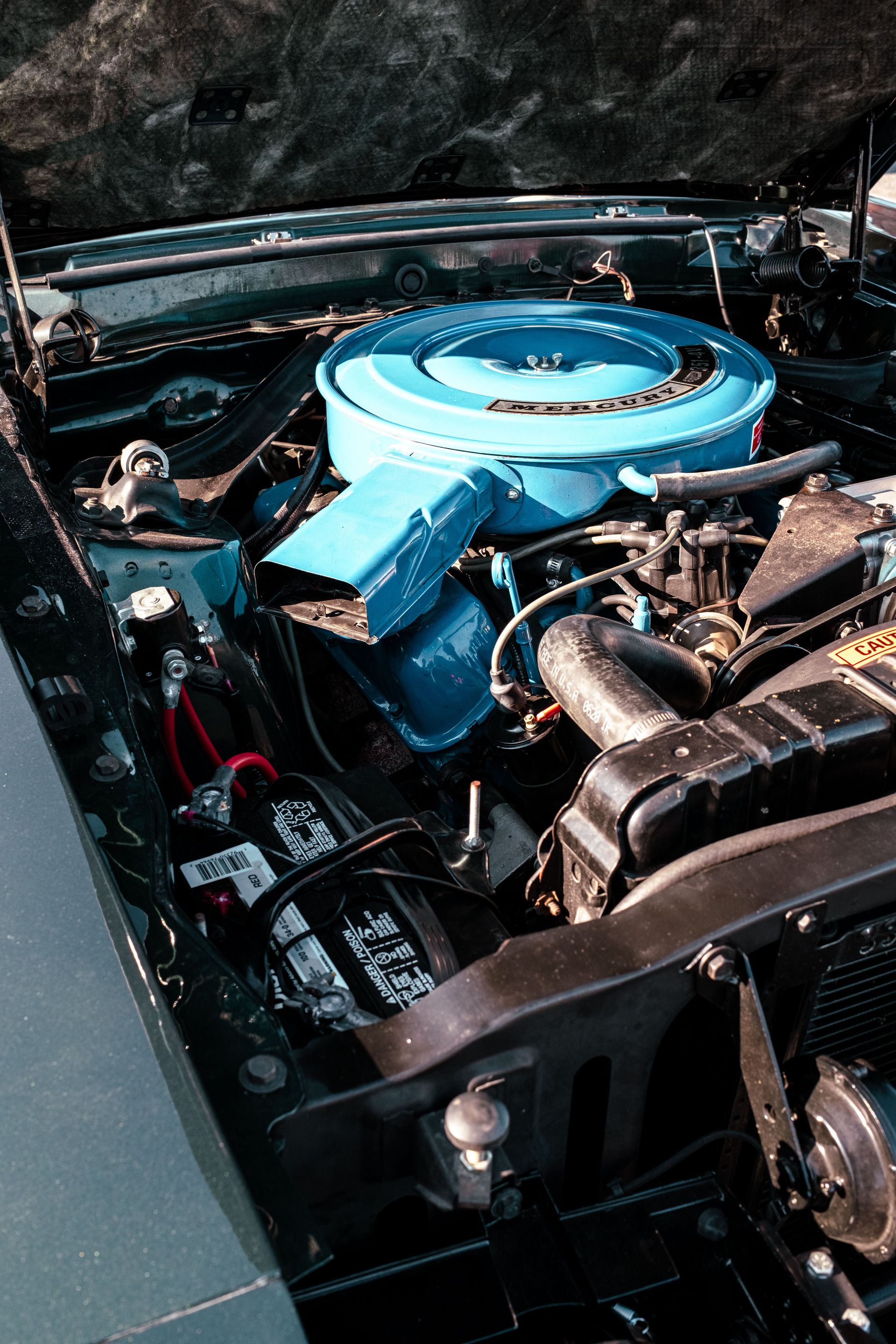 Close-up of a vintage car engine featuring a bright blue air filter, showcasing automotive details.